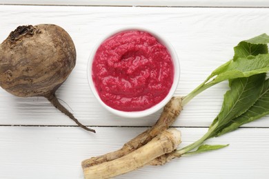 Photo of Tasty horseradish sauce with beetroot, vegetable and roots on white wooden table, flat lay