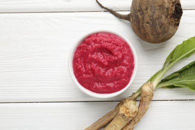 Photo of Tasty horseradish sauce with beetroot, vegetable and roots on white wooden table, flat lay. Space for text