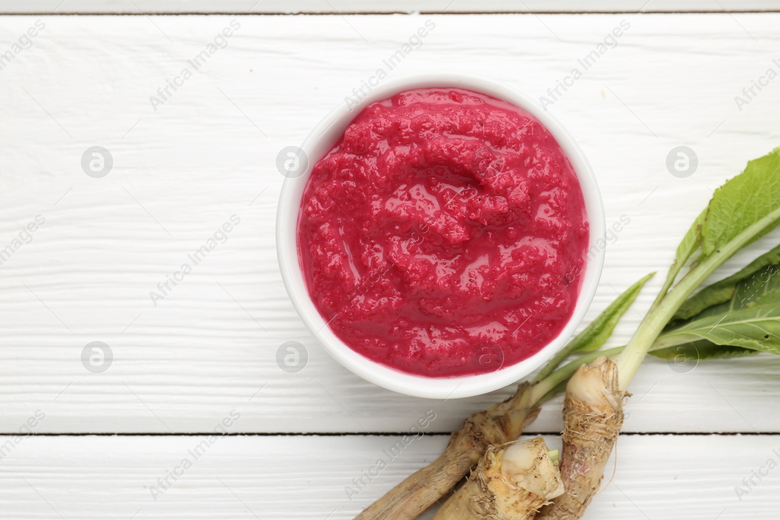 Tasty horseradish sauce with beetroot, vegetable and roots on white wooden table, flat lay. Space for text Photo of Tasty horseradish sauce with beetroot, vegetable and roots on white wooden table, flat lay. Space for text