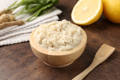 Photo of Tasty horseradish sauce and roots on wooden table, closeup