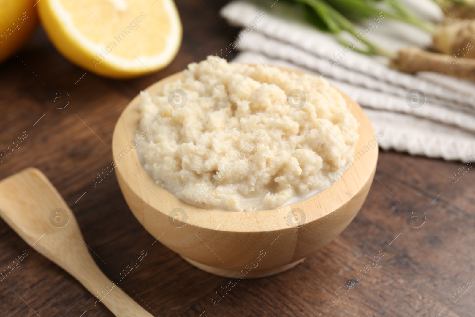 Photo of Tasty horseradish sauce and roots on wooden table, closeup