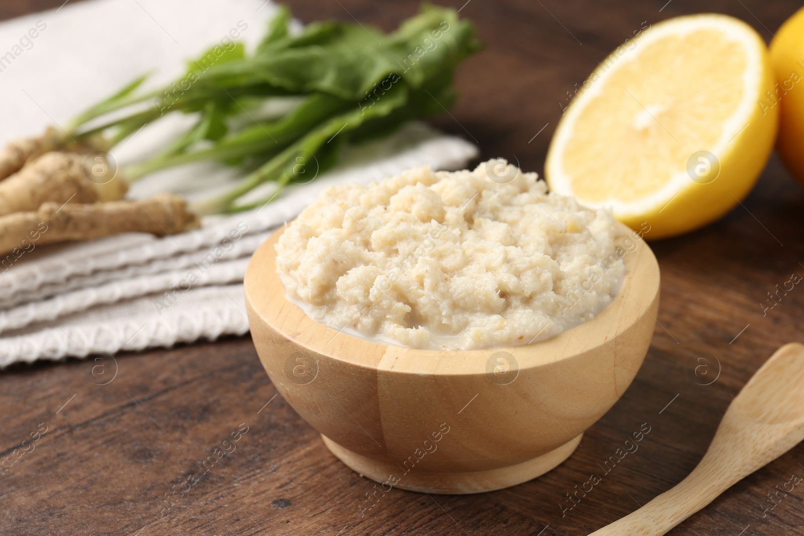 Photo of Tasty horseradish sauce and roots on wooden table, closeup