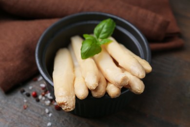 Photo of Pickled asparagus with basil and spices on wooden table, closeup