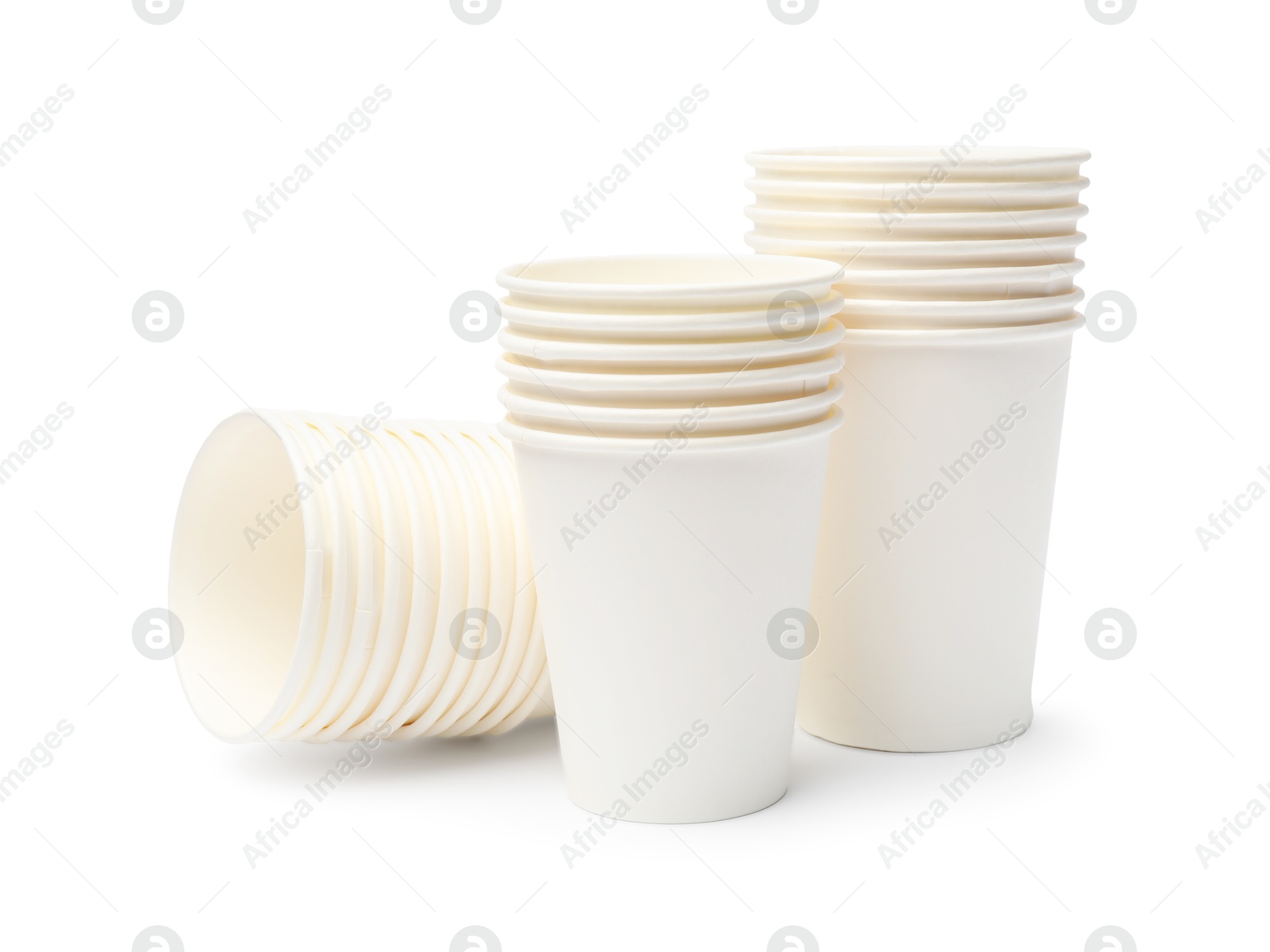 Photo of Disposable tableware. Stacks of paper cups isolated on white