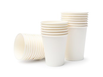 Photo of Disposable tableware. Stacks of paper cups isolated on white
