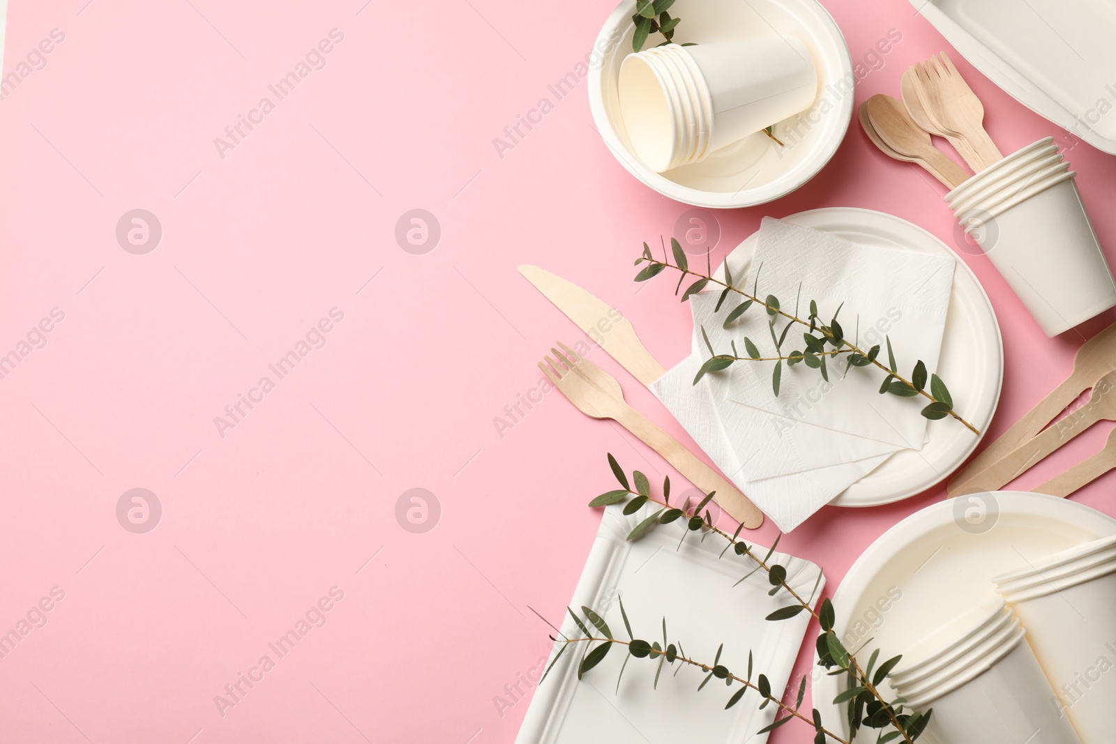 Photo of Set of disposable tableware and eucalyptus branches on pink background, flat lay. Space for text