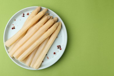 Photo of Pickled asparagus spears with spices on green table, top view. Space for text
