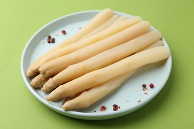 Photo of Pickled asparagus spears with spices on green table, closeup