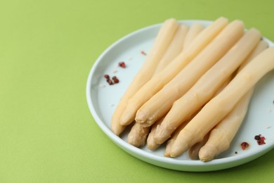 Photo of Pickled asparagus spears with spices on green table, closeup. Space for text