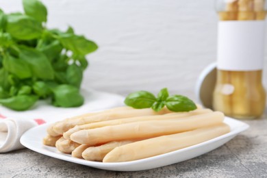 Photo of Pickled asparagus spears with basil on grey table, closeup