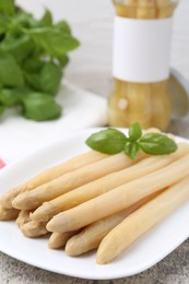 Photo of Pickled asparagus spears with basil on grey table, closeup