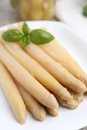 Photo of Pickled asparagus spears with basil on table, closeup
