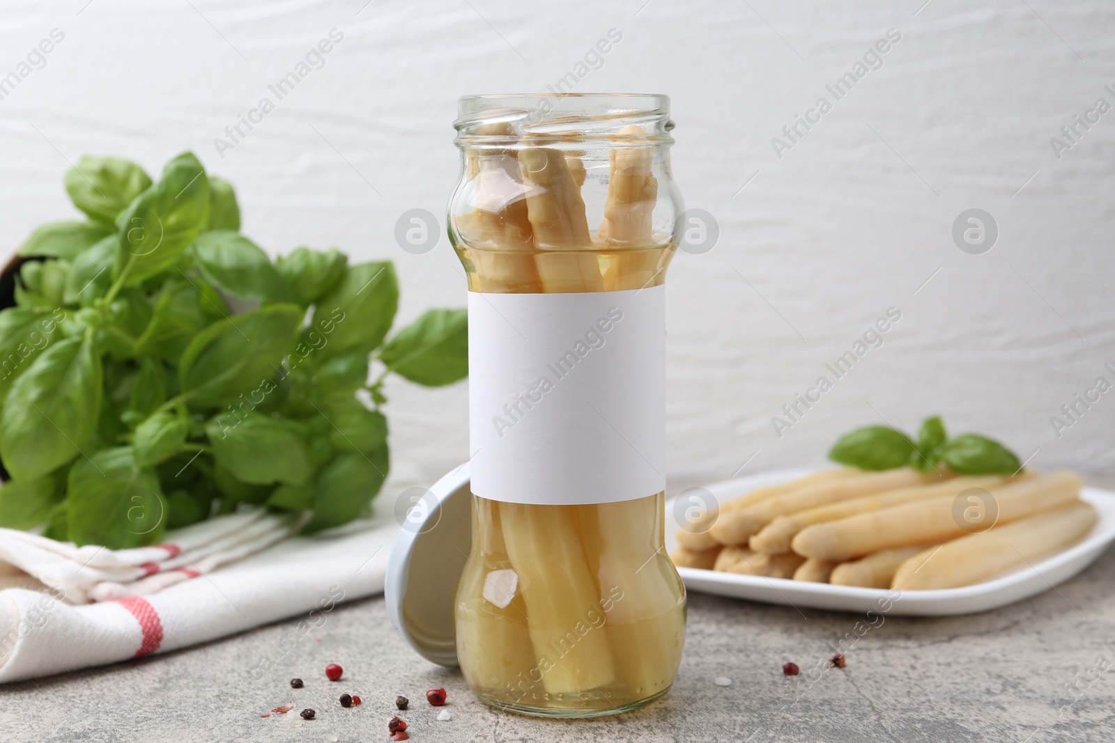 Pickled asparagus, spices and basil on light grey table, closeup Photo of Pickled asparagus, spices and basil on light grey table, closeup