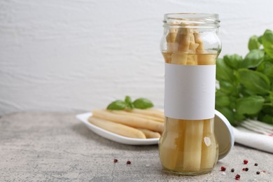 Photo of Pickled asparagus, spices and basil on light grey table, closeup. Space for text