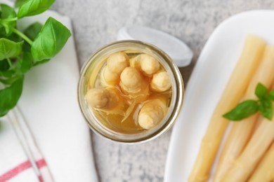 Photo of Pickled asparagus and basil on light grey table, flat lay