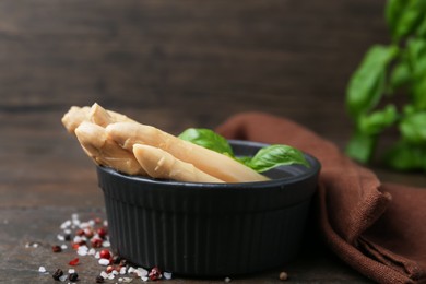 Photo of Pickled asparagus with basil and spices on wooden table, closeup