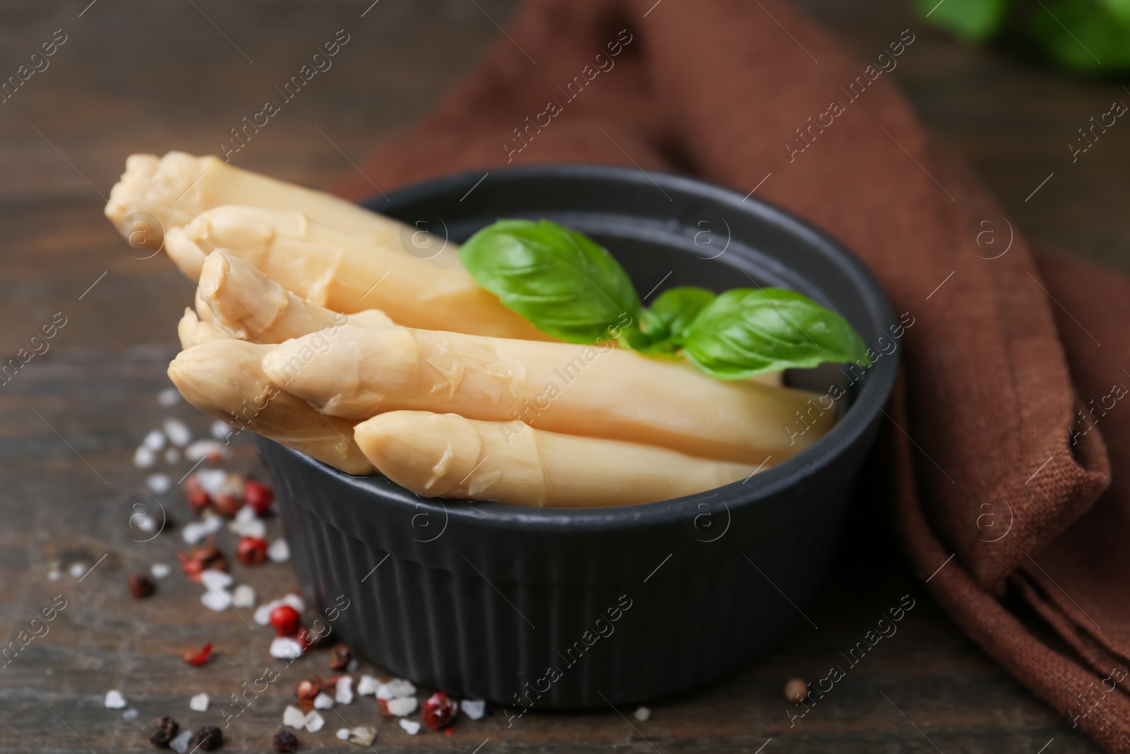 Pickled asparagus with basil and spices on wooden table, closeup Photo of Pickled asparagus with basil and spices on wooden table, closeup