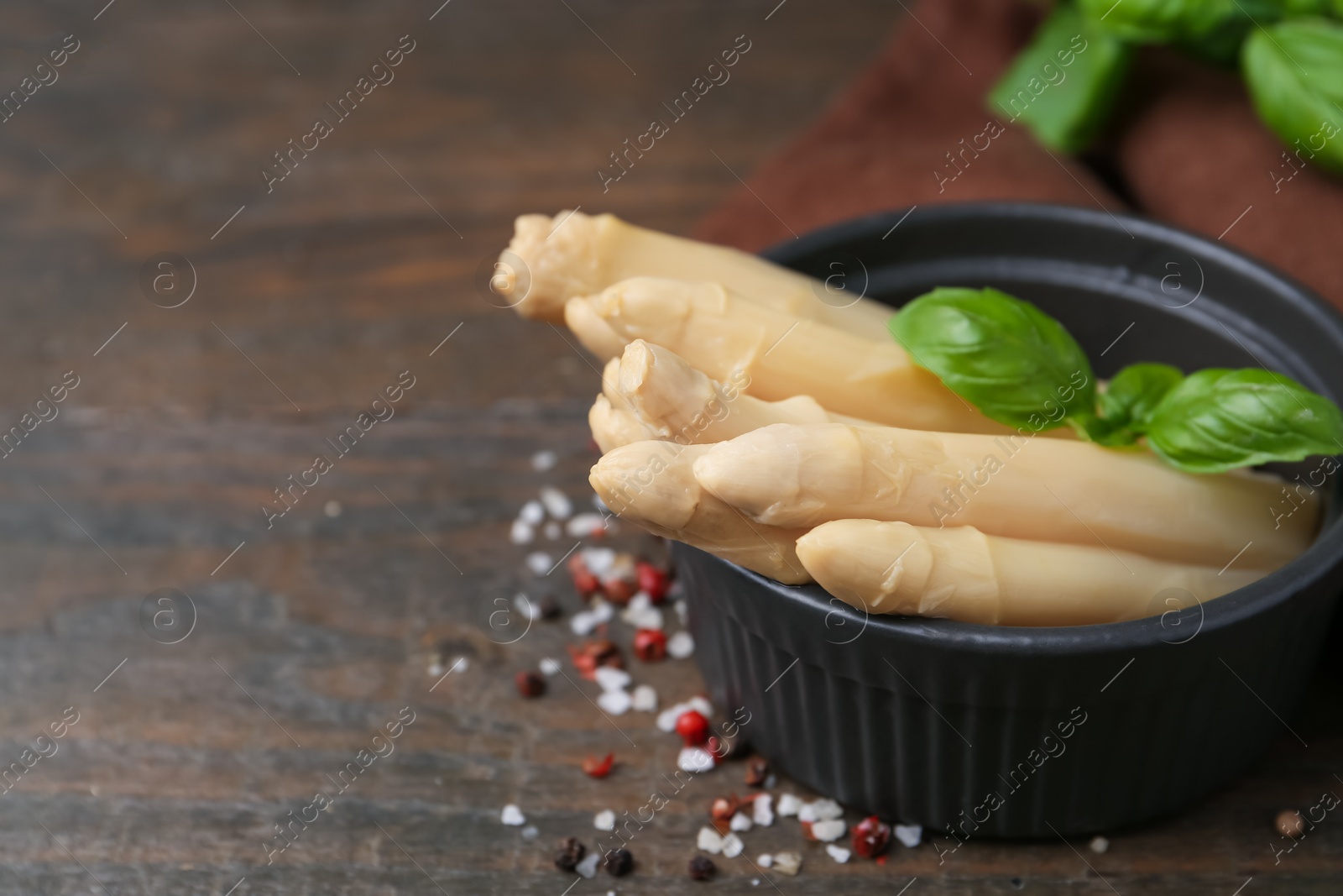 Pickled asparagus with basil and spices on wooden table, closeup. Space for text Photo of Pickled asparagus with basil and spices on wooden table, closeup. Space for text