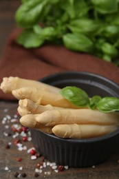 Photo of Pickled asparagus with basil and spices on wooden table, closeup