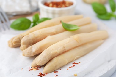 Photo of Pickled asparagus spears with spices and basil on table, closeup