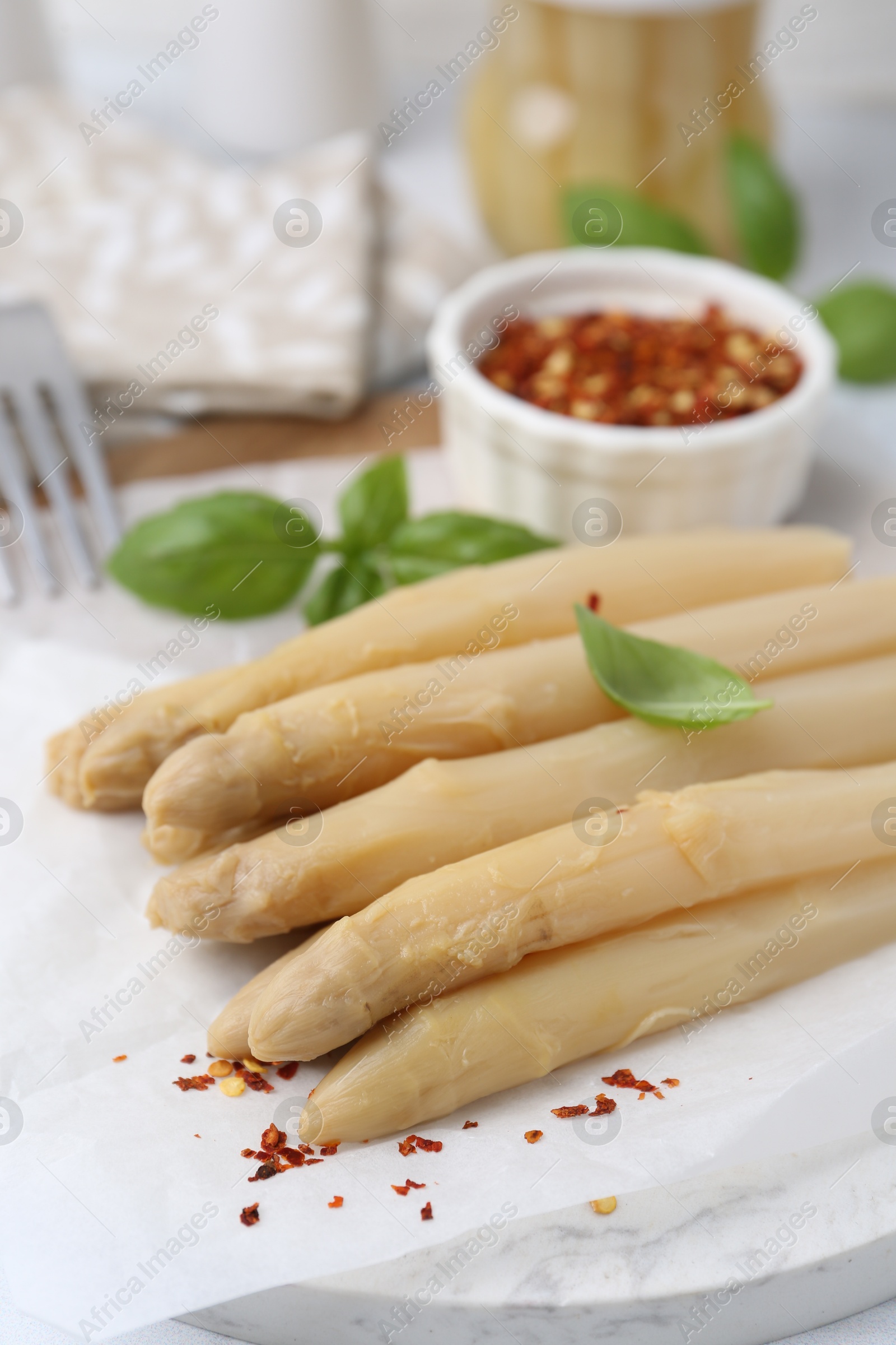Pickled asparagus spears with spices and basil on table, closeup Photo of Pickled asparagus spears with spices and basil on table, closeup