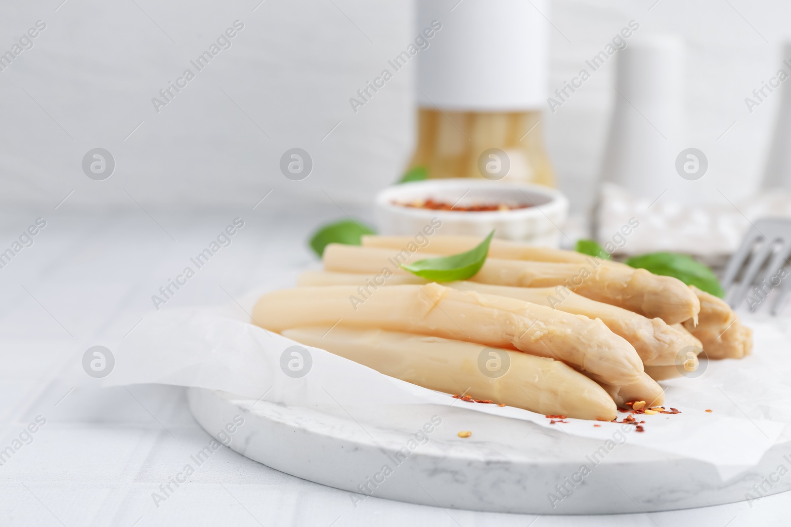 Pickled asparagus spears with spices and basil on white table, closeup Photo of Pickled asparagus spears with spices and basil on white table, closeup