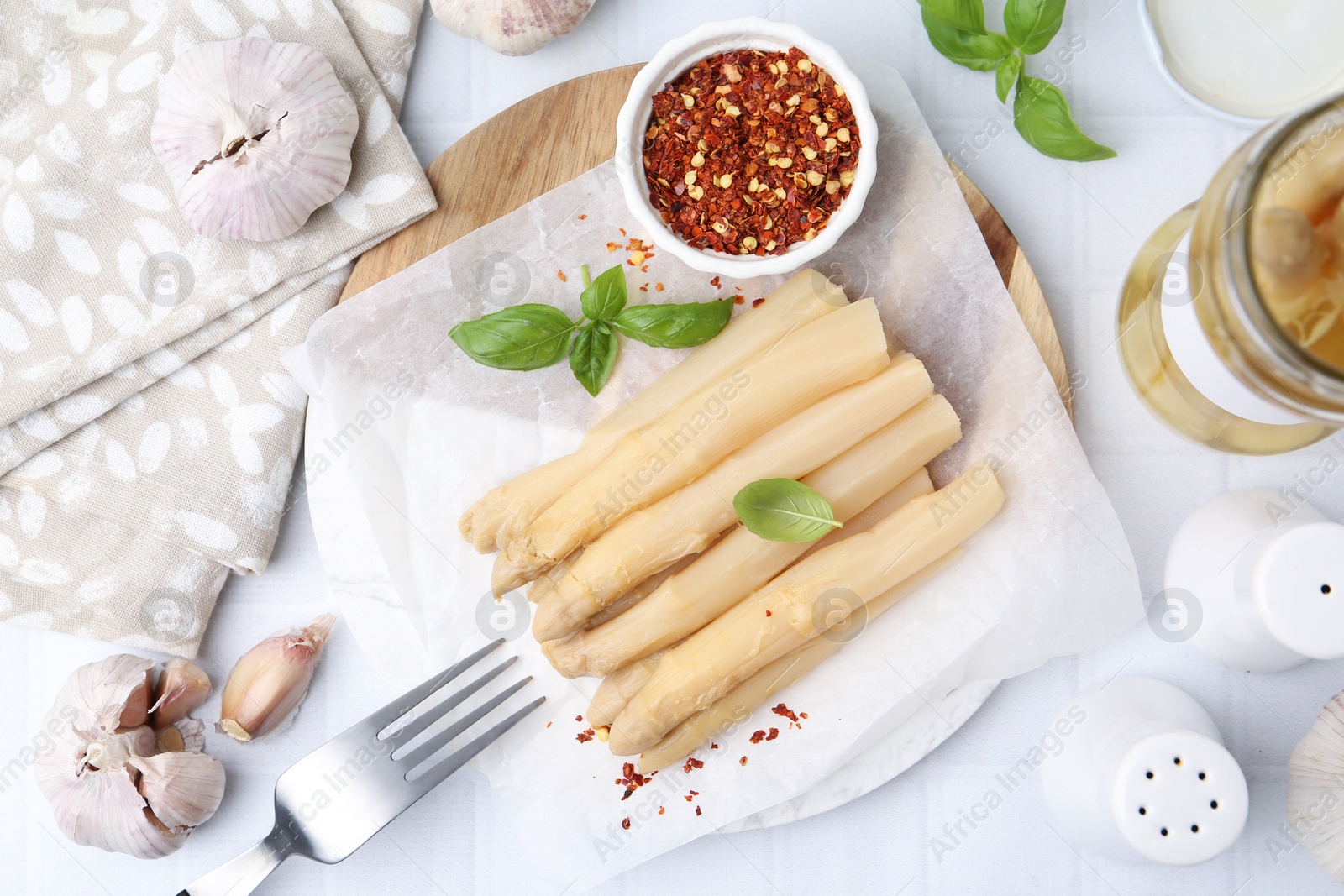 Photo of Pickled asparagus spears served on white tiled table, flat lay