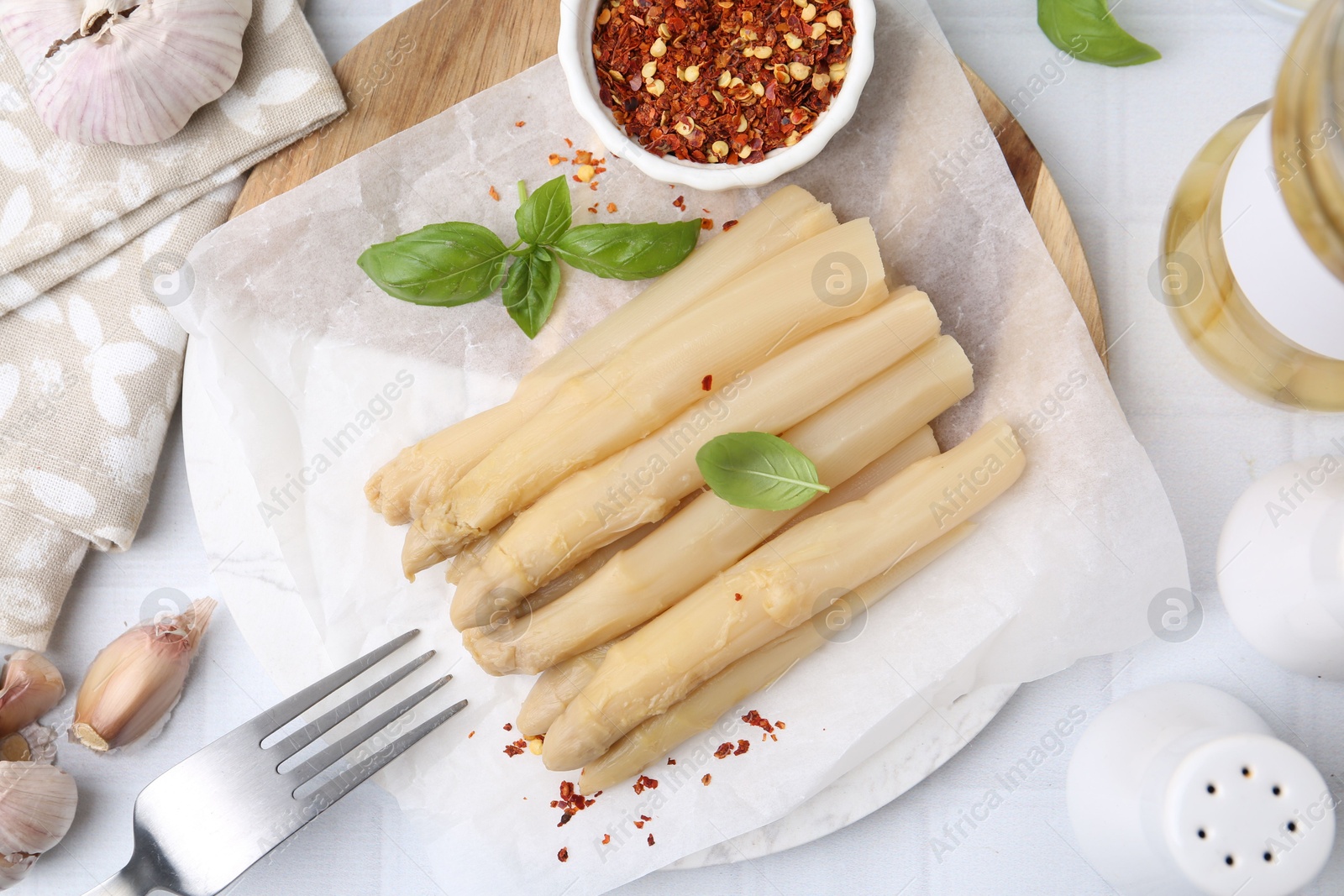 Photo of Pickled asparagus spears served on white tiled table, flat lay