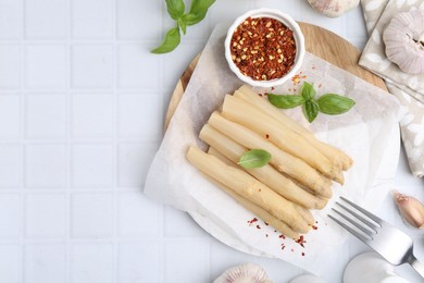 Photo of Pickled asparagus spears served on white tiled table, flat lay. Space for text