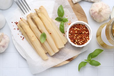 Photo of Pickled asparagus spears served on white tiled table, flat lay