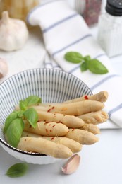 Photo of Pickled asparagus with spices, basil and garlic on white table, closeup