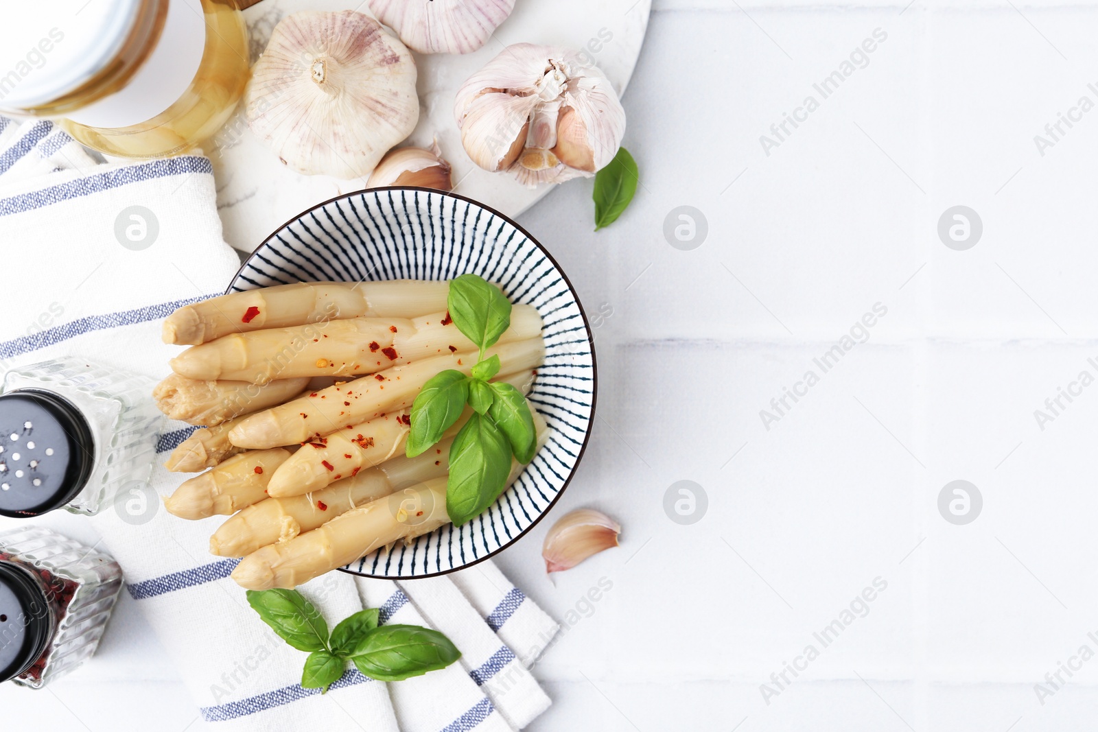 Pickled asparagus with spices, basil and garlic on white tiled table, flat lay. Space for text Photo of Pickled asparagus with spices, basil and garlic on white tiled table, flat lay. Space for text