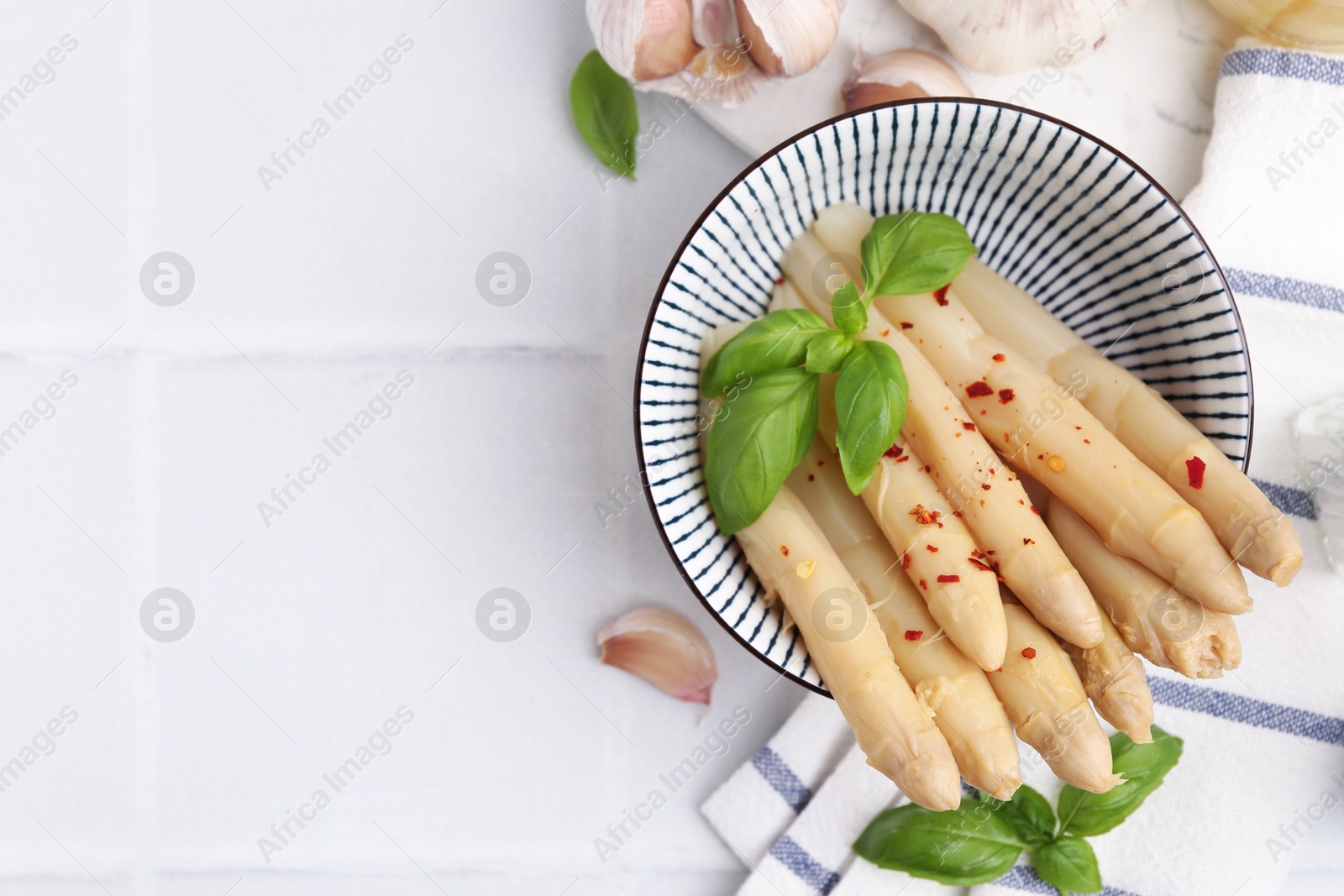 Pickled asparagus with spices, basil and garlic on white tiled table, flat lay. Space for text Photo of Pickled asparagus with spices, basil and garlic on white tiled table, flat lay. Space for text
