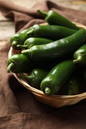 Photo of Ripe green jalapeno peppers in basket and towel on table, closeup