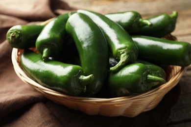 Photo of Ripe green jalapeno peppers in basket and towel on table, closeup