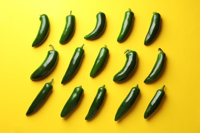 Photo of Green jalapeno peppers on yellow background, flat lay