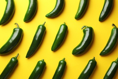 Photo of Green jalapeno peppers on yellow background, flat lay