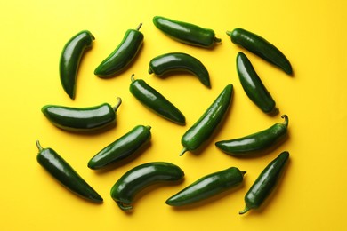 Photo of Green jalapeno peppers on yellow background, flat lay