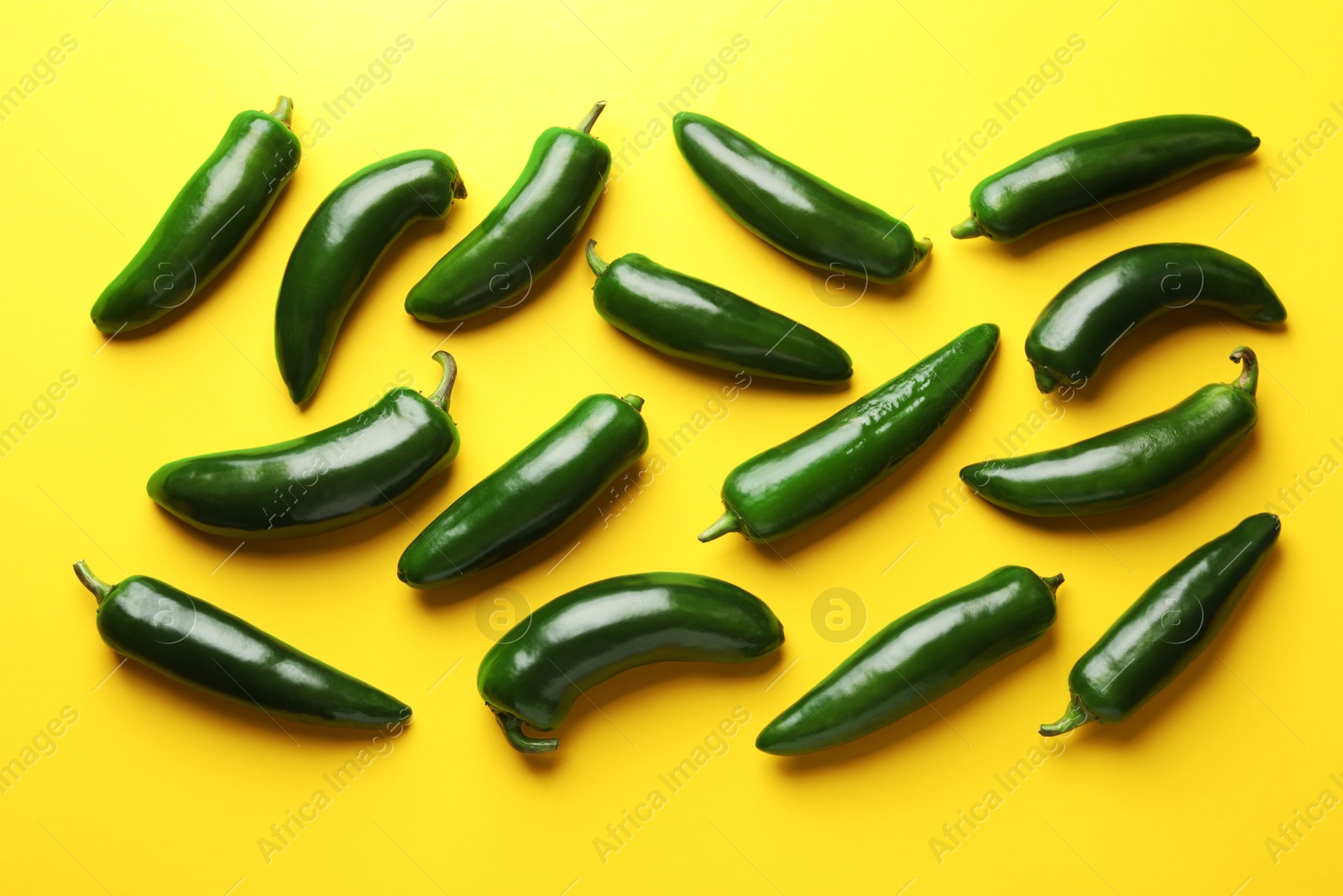 Green jalapeno peppers on yellow background, flat lay Photo of Green jalapeno peppers on yellow background, flat lay