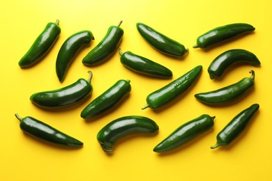 Photo of Green jalapeno peppers on yellow background, flat lay