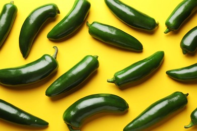 Photo of Green jalapeno peppers on yellow background, flat lay