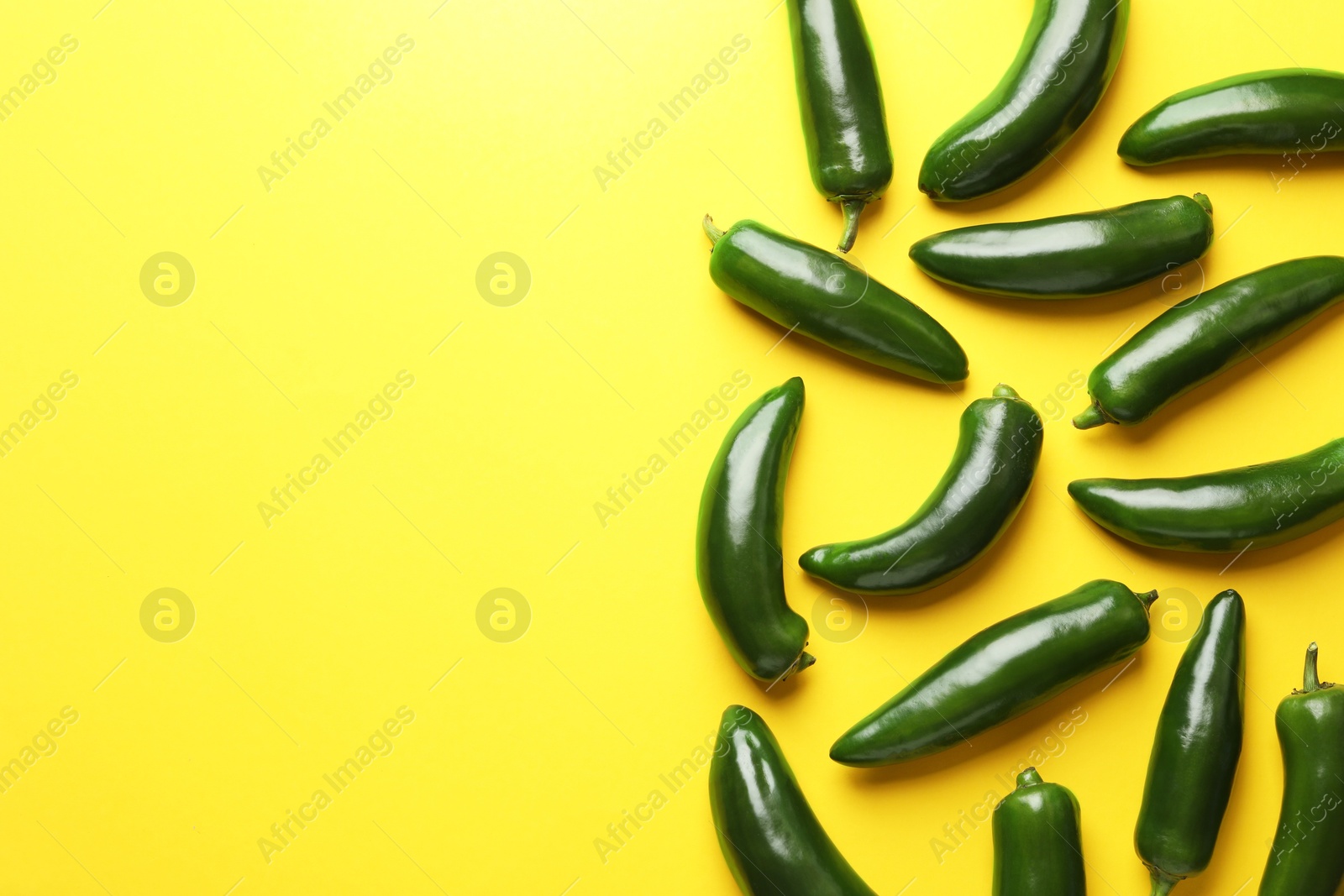 Green jalapeno peppers on yellow background, flat lay. Space for text Photo of Green jalapeno peppers on yellow background, flat lay. Space for text