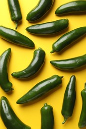 Photo of Green jalapeno peppers on yellow background, flat lay