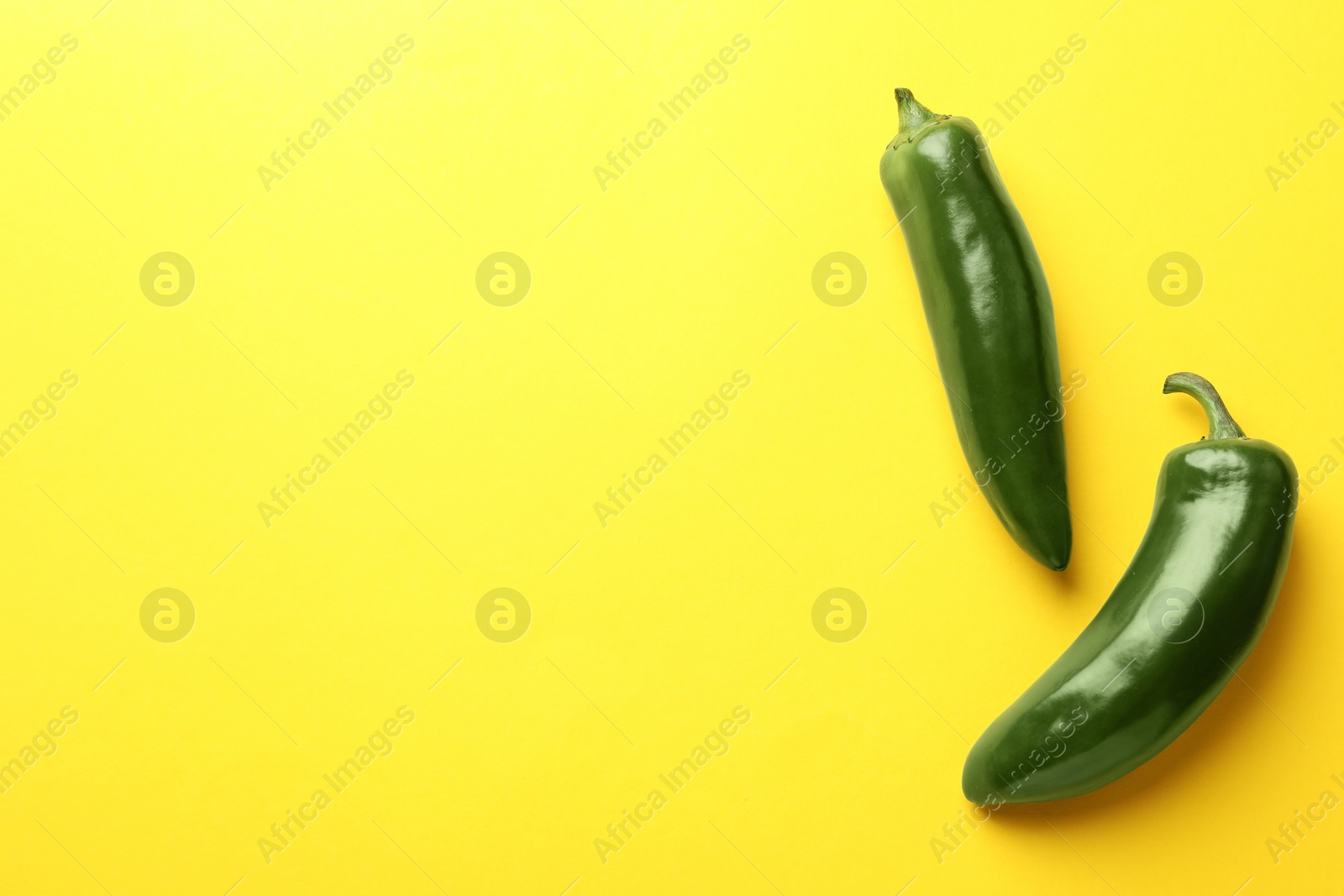 Green jalapeno peppers on yellow background, flat lay. Space for text Photo of Green jalapeno peppers on yellow background, flat lay. Space for text