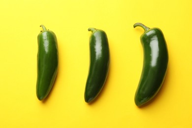 Photo of Green jalapeno peppers on yellow background, flat lay