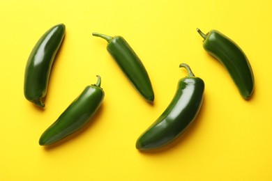 Photo of Green jalapeno peppers on yellow background, flat lay