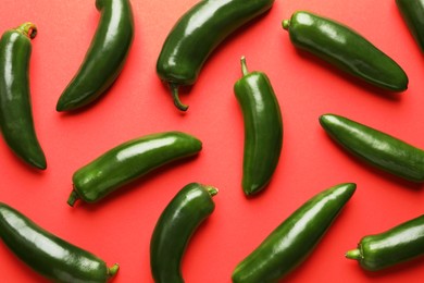 Photo of Green jalapeno peppers on red background, flat lay