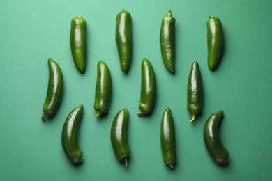 Photo of Ripe jalapeno peppers on green background, flat lay