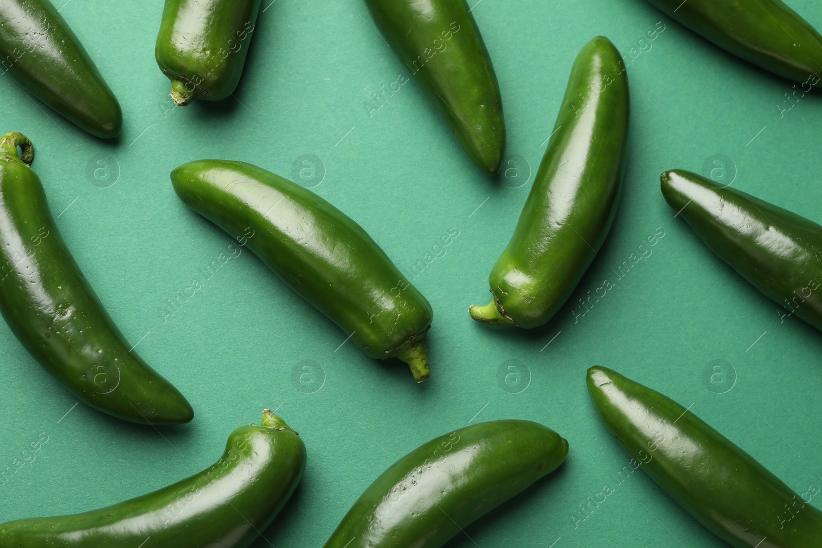 Ripe jalapeno peppers on green background, flat lay Photo of Ripe jalapeno peppers on green background, flat lay