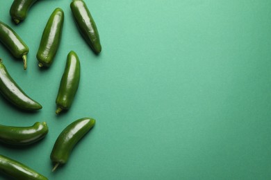 Photo of Ripe jalapeno peppers on green background, flat lay. Space for text